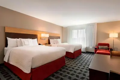 a hotel room with two beds and a red chair at TownePlace Suites by Marriott Pittsburgh Airport/Robinson Township in Robinson Township
