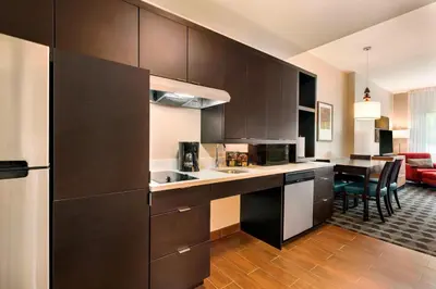 a kitchen with dark brown cabinets and a dining room at TownePlace Suites by Marriott Pittsburgh Airport/Robinson Township in Robinson Township