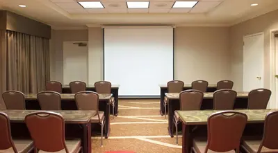 a conference room with tables and chairs and a screen at Hampton Inn & Suites Pittsburgh-Meadow Lands in Washington