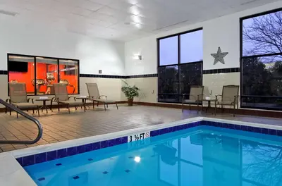 a swimming pool in a room with chairs and tables at Hampton Inn & Suites Columbus Hilliard in Hilliard
