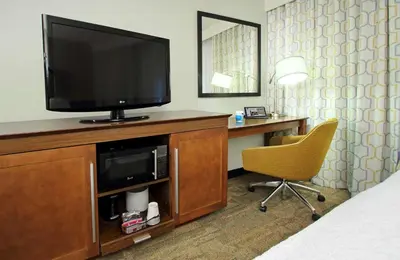 a hotel room with a television and a chair at Hampton Inn & Suites Columbus Hilliard in Hilliard