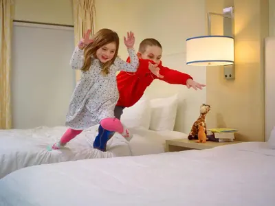 a boy and a girl jumping on a bed at Sonesta ES Suites Cincinnati - Sharonville East in Sharonville