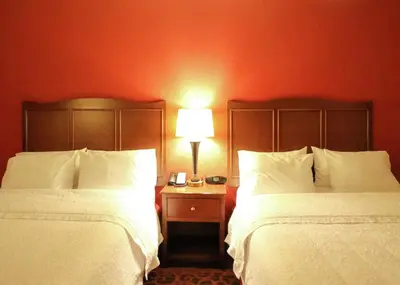 a hotel room with two beds and a table with a lamp at Hampton Inn Columbus-South in Grove City