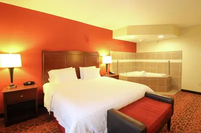 a hotel room with a large bed and a bath tub at Hampton Inn Columbus-South in Grove City