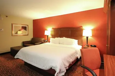a hotel room with a large bed and a chair at Hampton Inn Columbus-South in Grove City