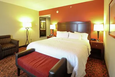 a hotel room with a large bed and a chair at Hampton Inn Columbus-South in Grove City