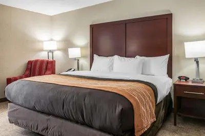 a hotel room with a large bed and a chair at Comfort Inn Blue Ash North in Blue Ash