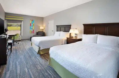 a hotel room with two beds and a desk at Hampton Inn Cincinnati Northwest Fairfield in Fairfield