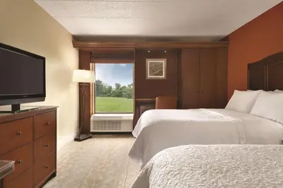 a hotel room with two beds and a flat screen tv at Hampton Inn Cincinnati Kings Island in Mason