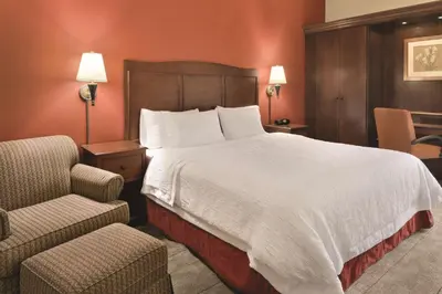 a hotel room with a large bed and a chair at Hampton Inn Cincinnati Kings Island in Mason