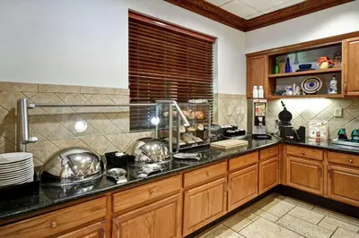 a kitchen with wooden cabinets and a black counter top at Homewood Suites by Hilton Cincinnati-Milford in Milford
