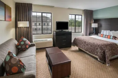 a hotel room with a bed and a couch and a tv at Staybridge Suites Columbus-Airport by IHG in Columbus