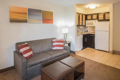 a living room with a couch and a kitchen at Staybridge Suites Columbus-Airport by IHG in Columbus