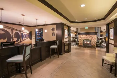 a lobby with a bar and a fireplace at Staybridge Suites Columbus-Airport by IHG in Columbus