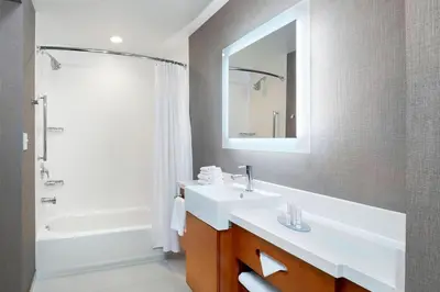 a bathroom with a sink and a mirror and a tub at SpringHill Suites by Marriott Dayton Beavercreek in New Germany