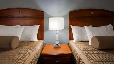 a hotel room with two beds and a lamp on a table at The Hotel at Dayton South in Dayton