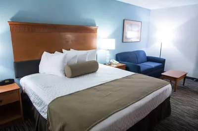 a hotel room with a bed and a blue chair at The Hotel at Dayton South in Dayton