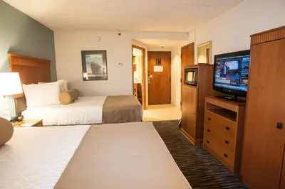 a hotel room with two beds and a flat screen tv at The Hotel at Dayton South in Dayton