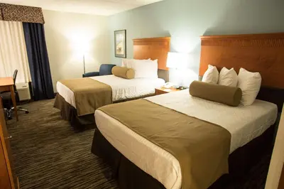 a hotel room with two beds and a desk at The Hotel at Dayton South in Dayton