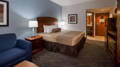a hotel room with a bed and a blue chair at The Hotel at Dayton South in Dayton