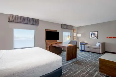 a hotel room with a bed and a desk with a television at Hampton Inn & Suites Muncie in Muncie