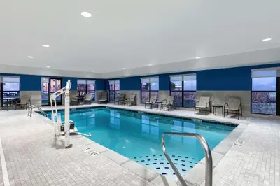 a pool in a hotel with tables and chairs at Hampton Inn & Suites Muncie in Muncie