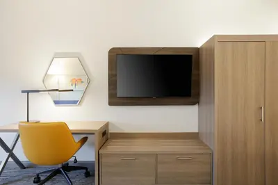 a room with a desk and a tv and a chair at Holiday Inn Express Hotel & Suites Cincinnati-Blue Ash by IHG in Blue Ash