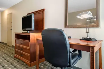 a room with a desk with a television and a chair at Quality Hotel Conference Center Cincinnati Blue Ash in Blue Ash