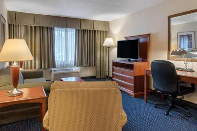 a hotel room with a desk and a living room at Quality Hotel Conference Center Cincinnati Blue Ash in Blue Ash