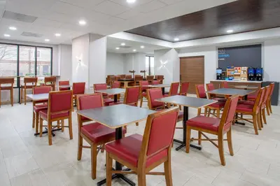 a dining room with tables and red chairs at Holiday Inn Express Hotel & Suites Fort Wayne by IHG in Fort Wayne
