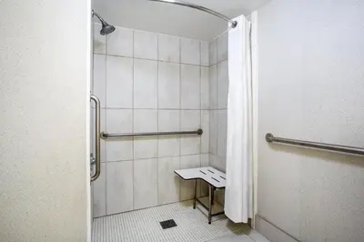 a bathroom with a shower with a bench in it at Holiday Inn Express Hotel & Suites Fort Wayne by IHG in Fort Wayne
