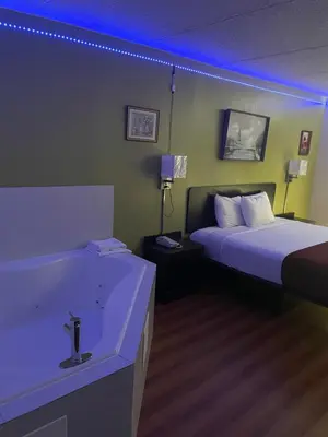 a bathroom with a tub and a bed and a bed and a sink at Willow Lodge Willoughby Cleveland in Willoughby