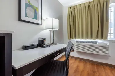 a room with a desk with a chair and a window at Quality Inn Coraopolis in Coraopolis
