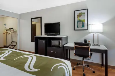 a hotel room with a bed and a desk with a television at Quality Inn Coraopolis in Coraopolis