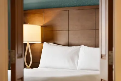 a bed with a wooden head board and a lamp at Staybridge Suites Fort Wayne by IHG in Fort Wayne
