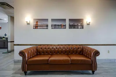 a brown leather couch in front of a wall with three paintings at Quality Inn I-75 West Chester-North Cincinnati in West Chester
