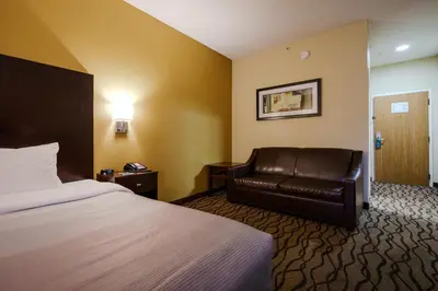 a hotel room with a bed and a leather chair at Quality Inn I-75 West Chester-North Cincinnati in West Chester