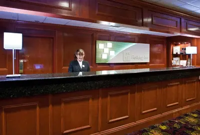 a woman standing behind a bar in a hotel room at Holiday Inn Cincinnati-Eastgate by IHG in Eastgate