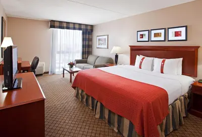 a hotel room with a large bed with a red blanket at Holiday Inn Cincinnati-Eastgate by IHG in Eastgate