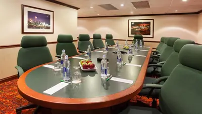 a conference room with a long table and green chairs at Holiday Inn Cincinnati Airport by IHG in Erlanger