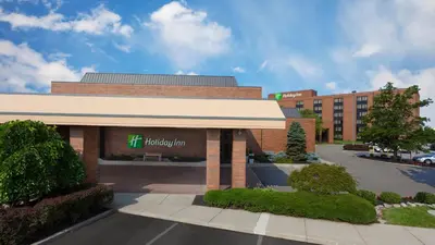 a building with a hilton inn sign in a parking lot at Holiday Inn Cincinnati Airport by IHG in Erlanger