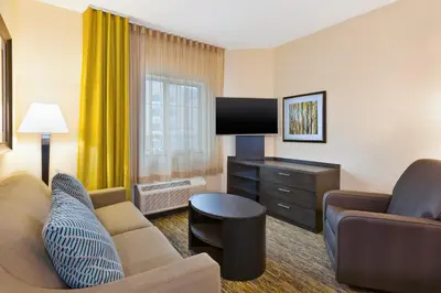 a living room with a couch and a tv in a hotel room at Candlewood Suites Washington North by IHG in Washington