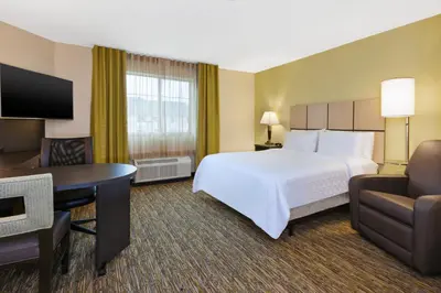 a hotel room with a large white bed and a desk at Candlewood Suites Washington North by IHG in Washington