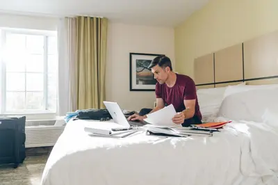 a man is working on his computer on a bed at Candlewood Suites Washington North by IHG in Washington
