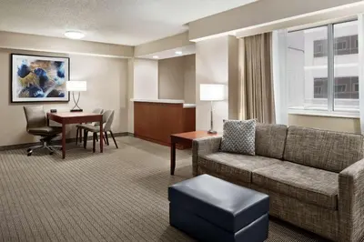 a hotel room with a couch and a table and a desk at Embassy Suites Cincinnati - RiverCenter in Covington