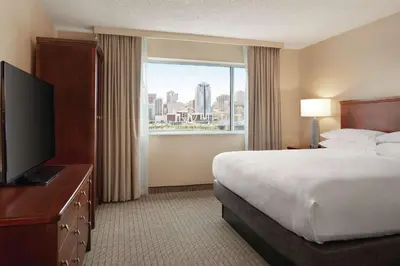 a hotel room with a bed and a large window at Embassy Suites Cincinnati - RiverCenter in Covington