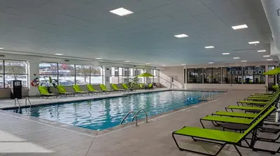 a large swimming pool with green chairs in a building at Holiday Inn Cleveland - South Independence by IHG in Independence
