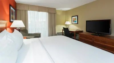 a hotel room with a bed and a flat screen tv at Holiday Inn Cincinnati-Riverfront by IHG in Covington