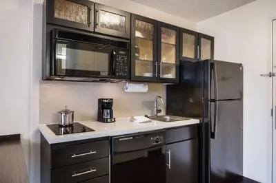 a kitchen with black cabinets and a stainless steel refrigerator at Sonesta Simply Suites Cleveland North Olmsted Airport in North Olmsted