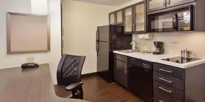 a kitchen with a black refrigerator and a chair at Sonesta Simply Suites Cleveland North Olmsted Airport in North Olmsted